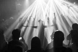 Tancerki z zespołu Samudra w wiankach na scenie podczas obrzędu Dziady Folkowe Ucho, widoczne jako sylwetki w mocnych snopach światła.